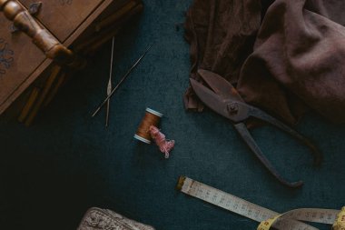 Terzinin eski alet ve aksesuarlarından oluşan bir hayat. Makas, mezura, deri kumaş, dikiş kutusu gibi. Malzemeleri karanlık ve kasvetli bir şekilde dikiyorum.