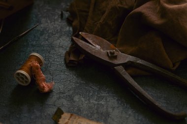 Terzinin eski alet ve aksesuarlarından oluşan bir hayat. Makas, mezura, deri kumaş, dikiş kutusu gibi. Malzemeleri karanlık ve kasvetli bir şekilde dikiyorum.
