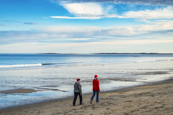 Hátul Egy Pár Mikulás Sapkában Sétálnak Óceán Partján Maine Usa — Stock Fotó