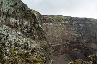 Napoli ili, Campania bölgesi, Güney İtalya, Avrupa ve AB 'deki Vesuvius Dağı' nın aktif volkan kraterinin sisli kenarında yürüyüş izleri. Taşlar, küller ve katılaşmış lavlarla dolu volkanik bir arazi.