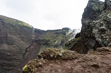 Napoli ili, Campania bölgesi, Güney İtalya, Avrupa ve AB 'deki Vesuvius Dağı' nın aktif volkan kraterinin sisli kenarında yürüyüş izleri. Taşlar, küller ve katılaşmış lavlarla dolu volkanik bir arazi.