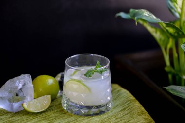 Koyu bir arka planda bardakta limon alkollü kokteyl.