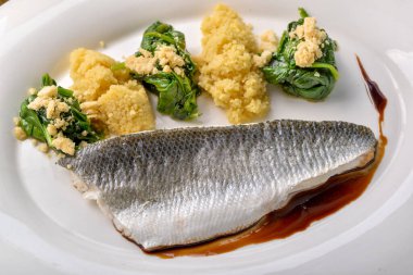 Beyaz tabakta balık filetosu ve garnitür.