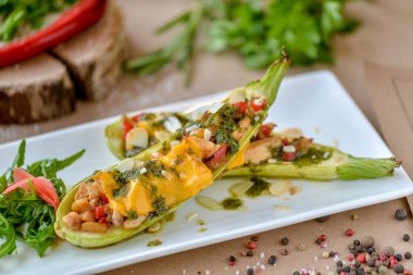 Beyaz dikdörtgen tabakta peynirli fırında kabak.