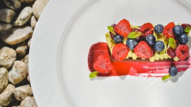 Arkaplanda yuvarlak beyaz bir tabakta meyveli çikolata tatlısı.