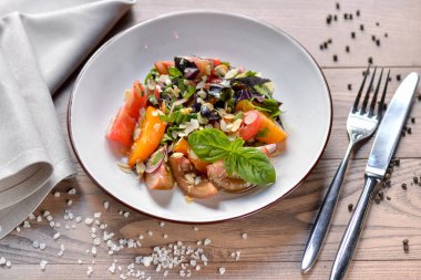 Tamatami fesleğenli Gürcü salatası ve masada güzel bir kil tabakta badem.