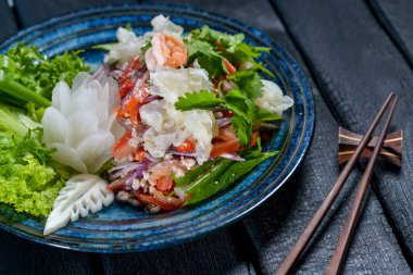 Tabağında salata olan taze deniz ürünleri.