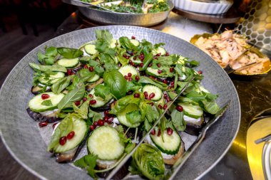 Restoranda salatalık ve fesleğenle servis edilen balık dilimleri.