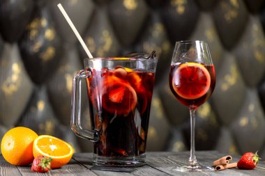 Bir sürahide sangria, yanında bir bardakla ahşap bir tahtada.