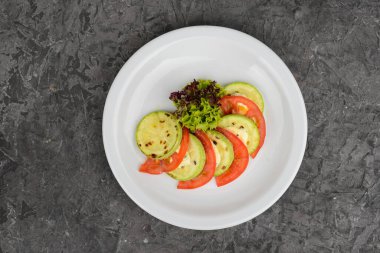 Taze domates salatası ve beyaz tabakta ızgara kabak.