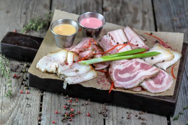 Tahtada dilimlenmiş domuz pastırması ve yeşil soğan.