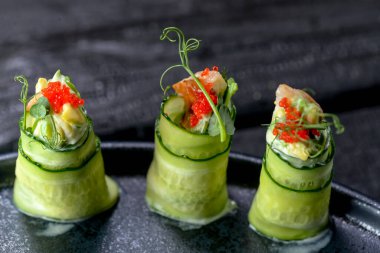 Birkaç rulo taze salatalık ve arka planda kırmızı havyar.