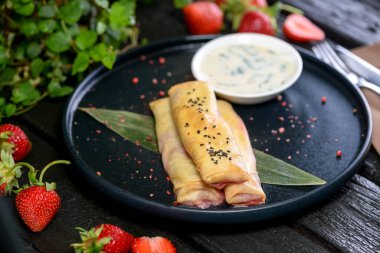 Koyu arkaplanda peynirli ve çilekli taze krep.