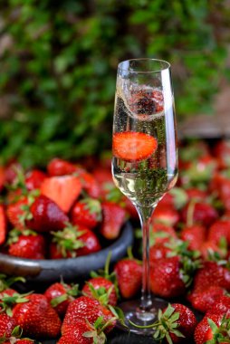 Arka planda çilek olan bir kadeh şampanya, yakın çekim.