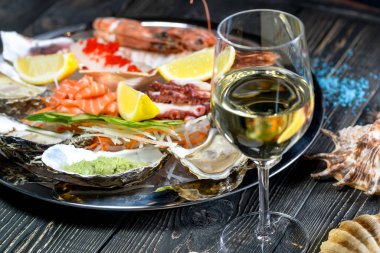 Tahta zemin üzerinde beyaz şarap bulunan taze deniz ürünleri.