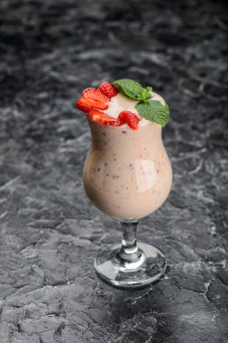 Masadaki bardakta çilekli süt.