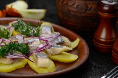 Patatesli ringa fileto ve soğanlı bir tabak.