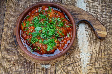 Masadaki kil tavada domates soslu Gürcü et tabağı. 