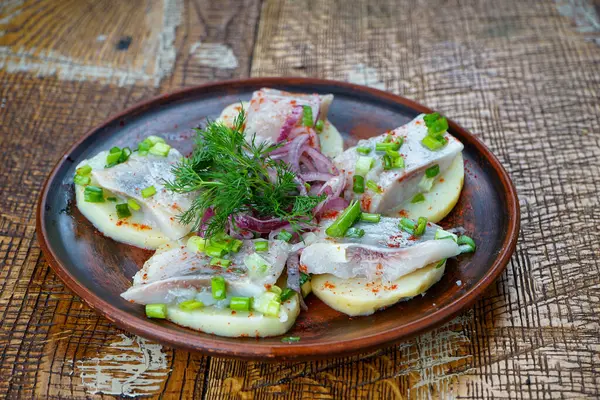 Patatesli ringa fileto, kilden bir tabakta soğan ve yeşillik.