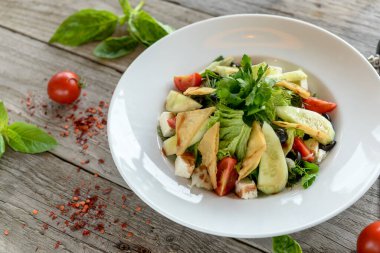 Arka planda tavuk, peynir ve sebzeli salata.