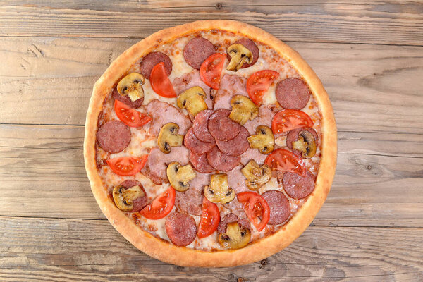 пицца с салями и помидорами, мясо и грибы на деревянном столе