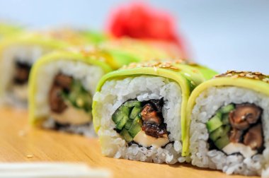 Ahşap tabakta servis edilen avokadoyla Japon suşisi ruloları.