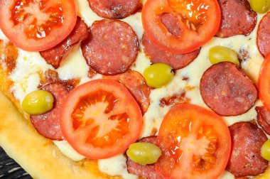 Salamlı pizza ve arka planda zeytin, yakın plan.