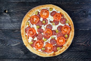 Arka planda salamlı ve sebzeli pizza, yakın plan.