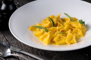 Beyaz tabakta otlarla süslenmiş ravioli pişirilmiş.