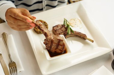 Kadın elleri ve kare tabakta ızgara et filetosu.