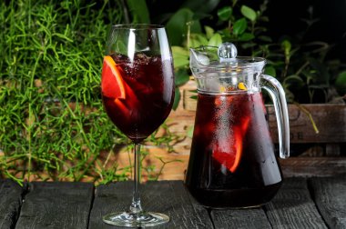 Arka planda meyveli bir sürahi limonata ve cam..