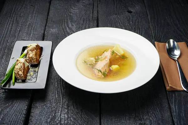 salmon soup with vegetables in white plate and bread