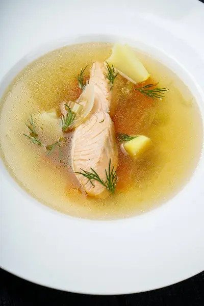 Beyaz tabakta sebzeli somon çorbası.