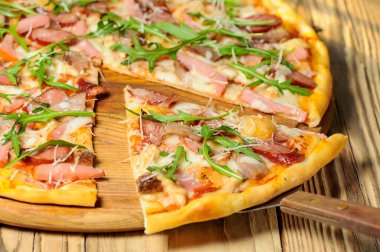 Jambonlu, peynirli ve roka aromalı pizza.