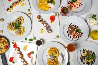 Suşi, omlet ve krepli çeşitli yiyeceklerin üst görüntüsü.