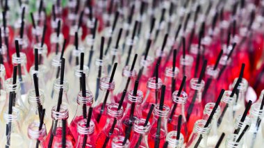 Arka planda içki ve pipet olan renkli şişeler, kapatın.