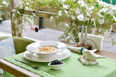 Verandada çiçekli yaban mersinli ve fındıklı yulaf lapası.