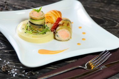 Salatalıklı kızarmış somon, patates püresi, kruvasan ve bıçaklı çatal.