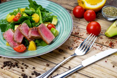 Avokado salatası, çatal, bıçak ve domatesli ton balığı.