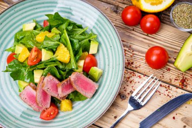 Avokado salatası, çatal, bıçak ve domatesli ton balığı.
