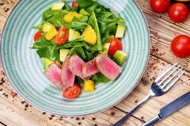Avokado salatası, çatal, bıçak ve domatesli ton balığı.
