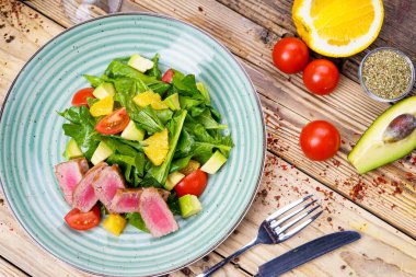 Avokado salatası, çatal, bıçak ve domatesli ton balığı.