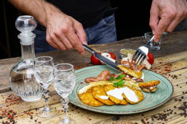Kızarmış pastırmalı erkek elleri, patatesli mantarlar ve votka.