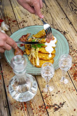 Kızarmış pastırmalı erkek elleri, patatesli mantarlar ve votka.