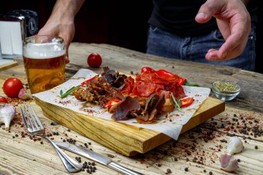 Adam ve tuzlanmış et çeşidi bira aperatifi ve bir bardak bira. 