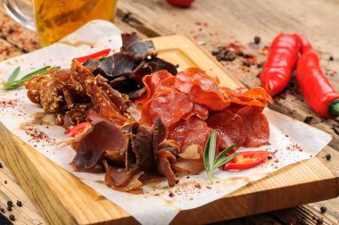 bira aperatiflerinin tuzlanmış et türleri bir bardak bira ve ahşap masa üzerinde biber.