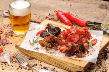 bira aperatiflerinin tuzlanmış et türleri bir bardak bira ve ahşap masa üzerinde biber.