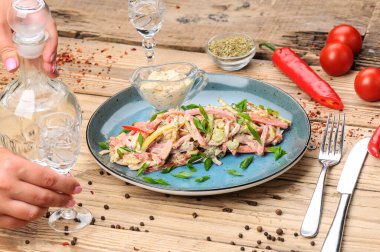 Jambon, soğan, salatalık ve salata soslu taze salata ile kadın elleri. 