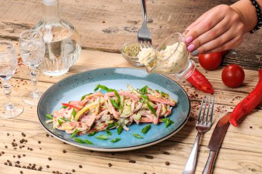 Jambon, soğan, salatalık ve salata soslu taze salata ile kadın elleri. 