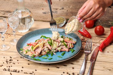 Jambon, soğan, salatalık ve salata soslu taze salata ile kadın elleri. 